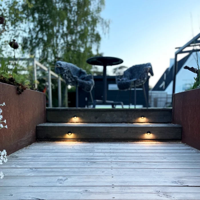 Aries Svart monterad i trätrappans sättsteg mellan rostfärgade sidopaneler | Molectric