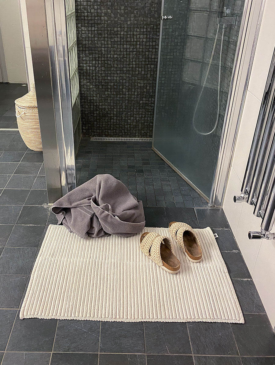 Ribb natur från Etol, naturfärgad bomullsmatta i badrumsmiljö med tofflor och handduk | Molectric